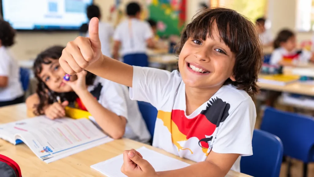 Estudiante del Colegio Alemán de Barranquilla sonríe y levanta el pulgar durante una actividad en el aula, reflejando confianza y entusiasmo por aprender.
